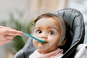 Cute, sweet and girl baby eating puree for lunch, dinner or snack in her high chair at home. Child development, food and