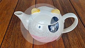 Cute tea pot on wood background