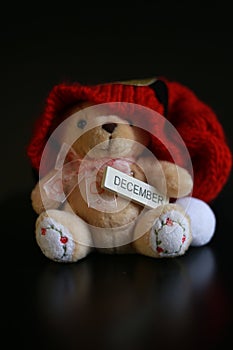 Cute teddy bear with red christmas hat isolated on dark black background.
