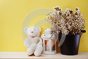 Cute teddy bear sitting on wooden table with dried flower home decoration