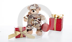 Cute teddy bear in soldier uniform and xmas presents  against white background