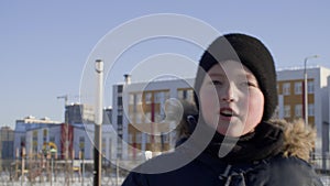 Cute teen boy walking and talking outdoors at wintertime