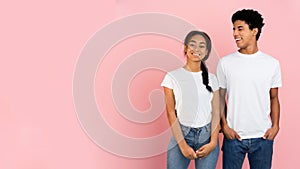 Cute teen couple posing on pink background with free space