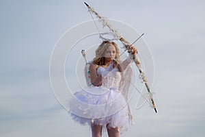 Cute teen cupid on the cloud - sky background. Lovely and cute youth. Lovely girl cupid with bow and arrow is ready to