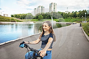 Cute teen girl is on a bike ride in a city park.