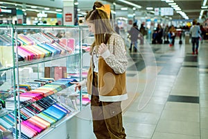Cute teen girl chooses a mobile phone and protection for him. multi-colored phone cases in the mall. Shopping in the store,