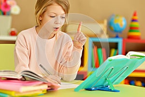 Portrait of cute teen girl doing homework in her room