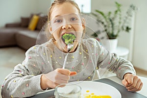 Cute teen girl eating green fresh broccoli