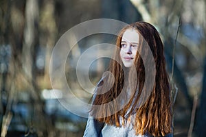 Cute teen girl with fiery red hair posing in the pine park