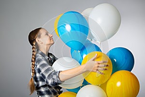 Cute teen girl holding a bunch of colorful balloons