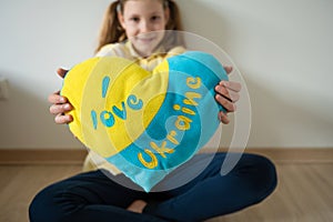 Cute teen girl holding a pillow of Ukrainian flag colors
