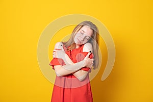 Cute teen girl hugs herself touches shoulders expresses self love smiles pleasantly