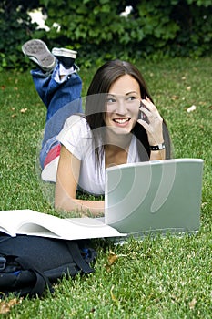 Cute teen girl laying down on the grass studying