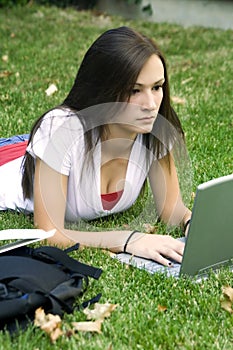 Cute teen girl laying down on the grass studying