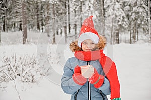 cute teen girl opens gift box, christmas present, outdoor in winter, child in scarf, mittens and santa hat
