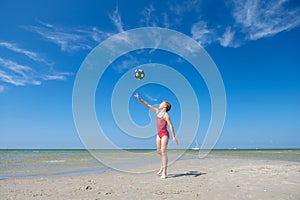 Cute teen girl playing and having fun with ball on beach at sunny summer day