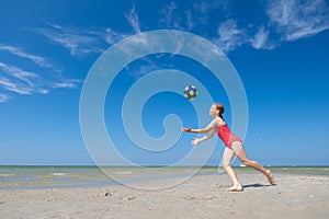 Cute teen girl playing and having fun with ball on beach at sunny summer day