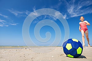 Cute teen girl playing and having fun with ball on beach at sunny summer day