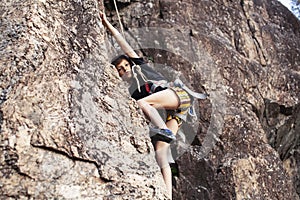 Cute teen kid climbing on rock with insurance, lifestyle sport people concept