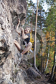 Cute teen kid climbing on rock with insurance, lifestyle sport people concept