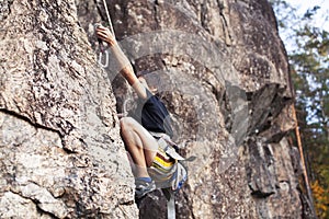 Cute teen kid climbing on rock with insurance, lifestyle sport people concept