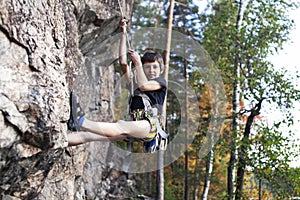 Cute teen kid climbing on rock with insurance, lifestyle sport people concept