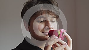 Cute Teenage Boy holding a cut Dragon Fruit in his hands next to his face, sniffing it and smiling on a white background