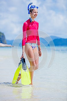 Teenage girl in bikini carrying scubadiving equipment photo