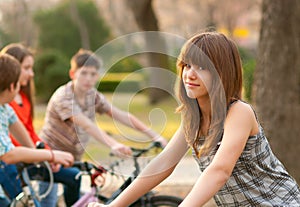 Cute teenage girl with her friends on bicycles