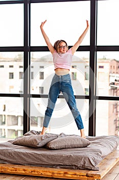 Cute teenage girl jumping on the bed in her room