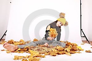 Teen girl sitting on dried leaves in photo atelier photo
