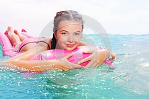 Cute teenage girl laying on matrass in sea