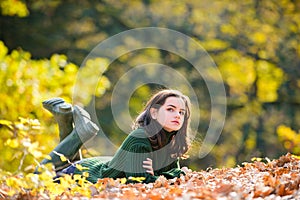Cute teenage girl lying on autumn maple leaves at fall outdoors. Beautiful fall time in nature.