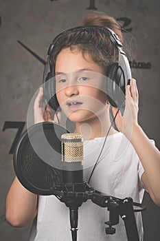 Cute teenage girl is recording a song in the studio. Close-up. Vertical shot
