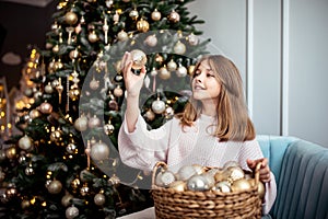 Cute teenage girl in a room with a decorated Christmas tree. The winter holidays.