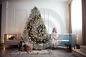 Cute teenage girl in a room with a decorated Christmas tree. The winter holidays.