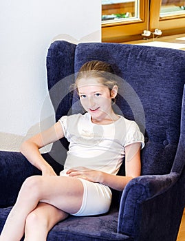 Cute teenage girl sitting in arm-chair