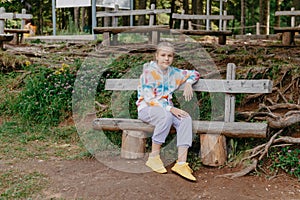 Cute teenage girl sitting on a wooden bench in the park