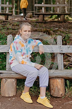 Cute teenage girl sitting on a wooden bench in the park