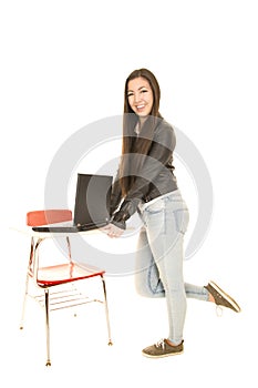 Cute teenage girl standing by a desk with a computer