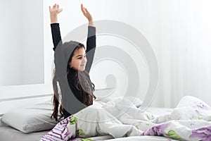 Cute teenage girl stretching on the bed in her room having fun.