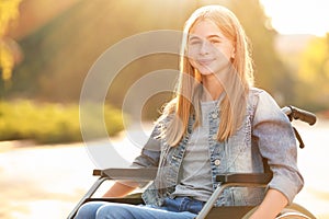 Cute teenage girl in wheelchair outdoors
