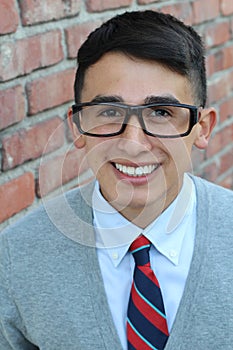 Cute teenager boy in formal high school uniform and glasses smiling