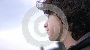 Cute teenager with curly hair against the blue sky 4k, slow-motion shooting