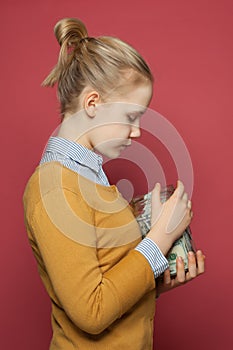 Cute teenager girl holding money cash in jar. Students fees, responsibility and saving money concept