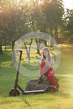 Cute teenager girl relaxing after riding by electric kick scooter