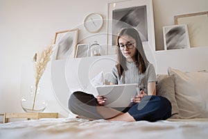 Cute teenager girl using tablet lying on bed at home