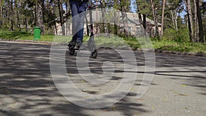 Cute teenager rides on kick scooter in the park