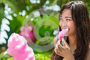 Cute Thai girl is eating pink candyfloss