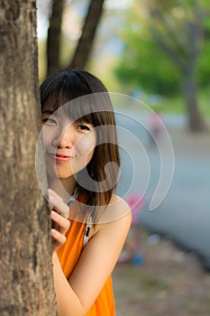 Cute Thai girl hiding behind the tree